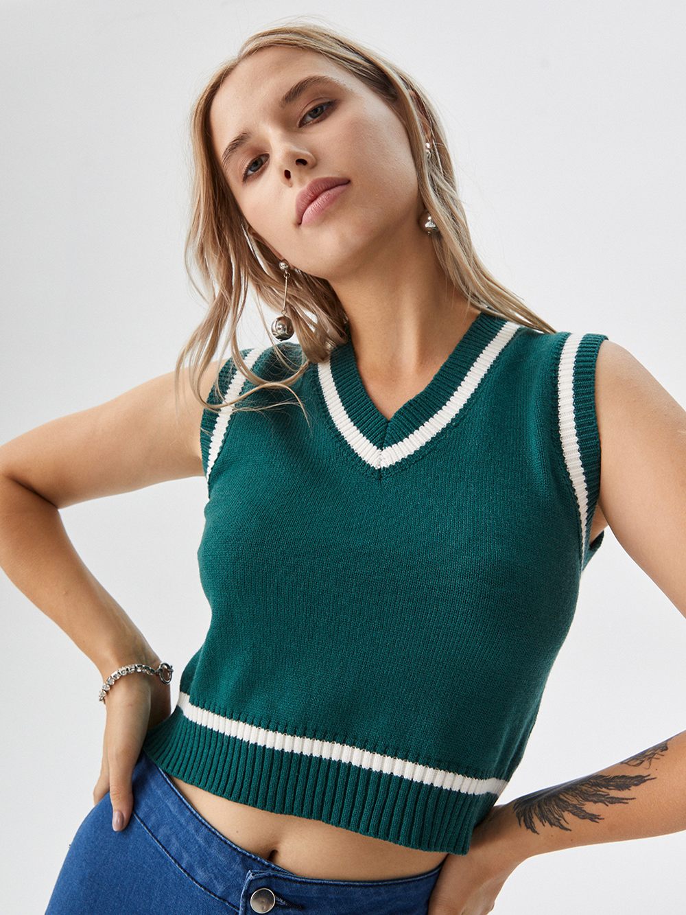 Professional AI product photography featuring a studio model wearing a sleeveless knit top in a minimalist white studio, trustworthy style.